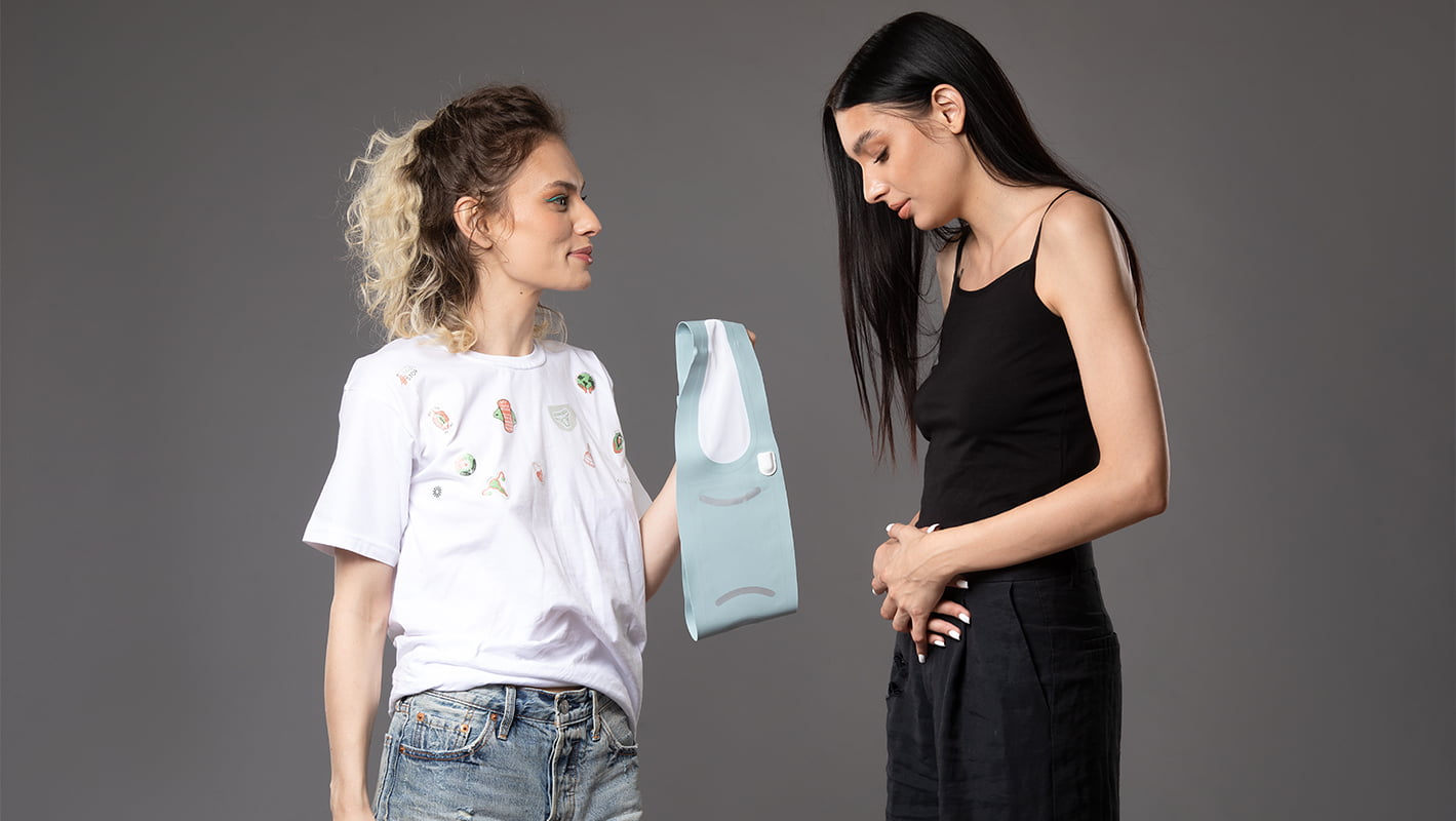 Femeie oferind sprijin altei femei care se confruntă cu dureri menstruale, simbolizând empatia și soluțiile moderne pentru confortul în timpul menstruației.