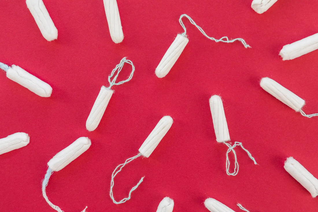Tampoane albe plasate pe fundal roșu intens, ilustrând produsele menstruale convenționale.