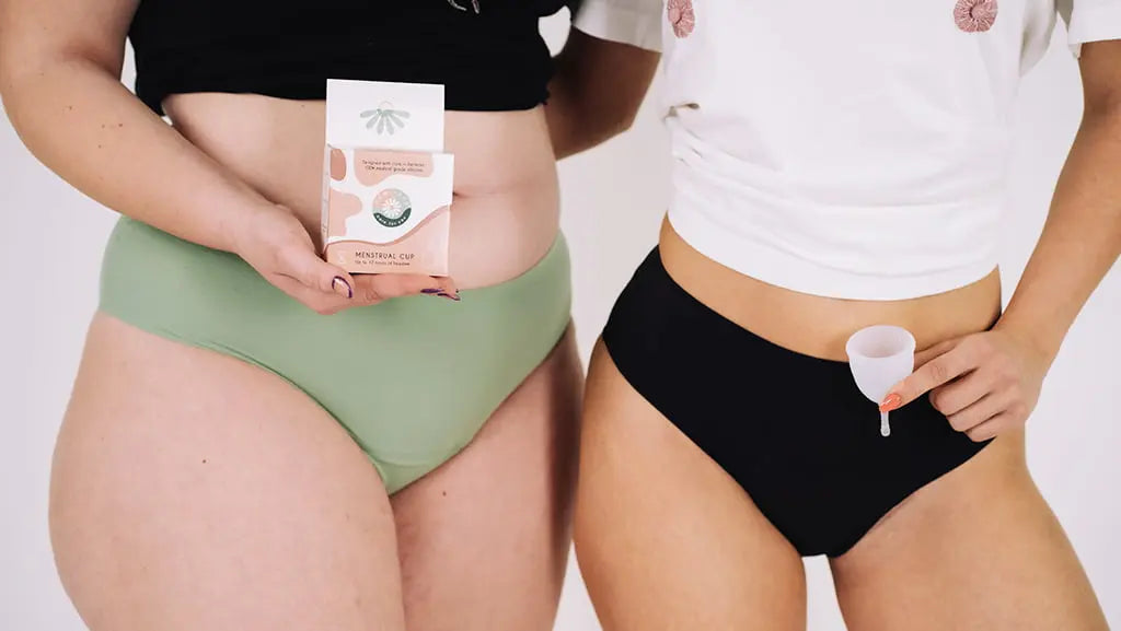 Două femei în lenjerie menstruală, una ținând o cutie cu cupa menstruală Femi.Eko®, cealaltă prezentând cupa – un simbol al diversității, confortului și alegerii sustenabile.